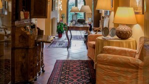 A cozy living room with a wooden ceiling, a fireplace, a sofa, and a coffee table. - Piazza Nova Guest House (Ferrara)