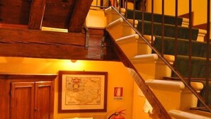 A wooden staircase with a metal railing leading to a landing. A fire extinguisher is mounted on the wall beside the staircase. - Piazza Nova Guest House (Ferrara)