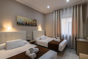 Una camera d'albergo con due letti, un quadro appeso al muro e una finestra con tende.