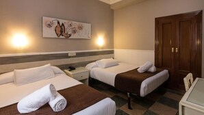 A hotel room with two beds, a nightstand, a desk, and a wooden wardrobe. - Hotel Mexico (Madrid)