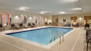 A large indoor swimming pool with tiled flooring and multiple lounge chairs around the perimeter. - Homewood Suites by Hilton Kalamazoo-Portage (Portage)
