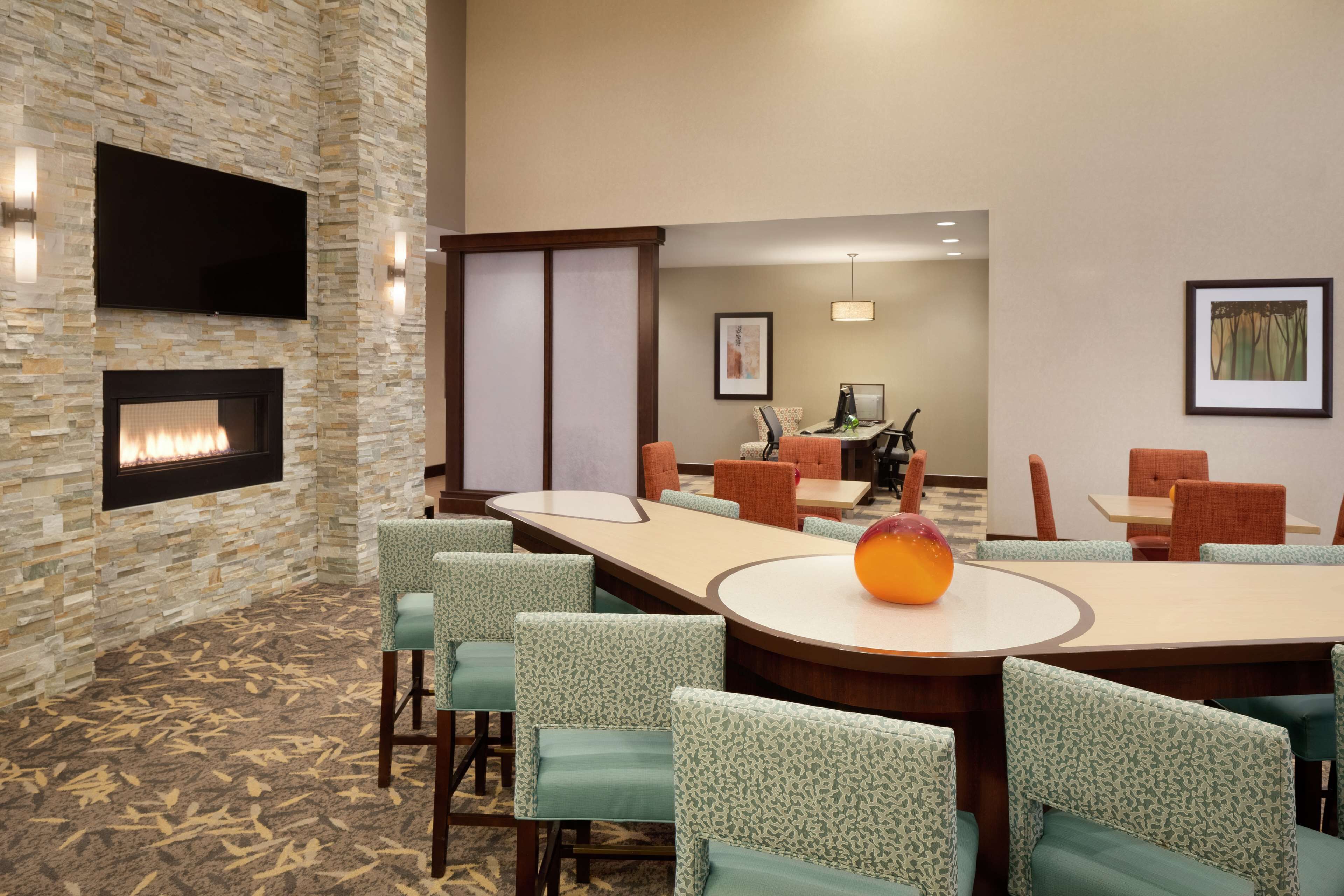A conference room with a stone wall, a flat-screen TV, a fireplace, and a round table with chairs.