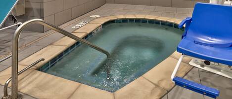 Un jacuzzi con una escalera metálica y una silla azul.
