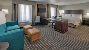 A hotel room with a bed, a desk, a chair, a sofa, and a TV. - Hampton Inn & Suites Albuquerque Airport (Albuquerque)