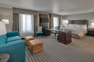 Habitación de hotel con cama, escritorio, silla, sofá y televisor.