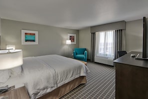 Ein Hotelzimmer mit Bett, Schreibtisch, Stuhl und einem Vorhangfenster.