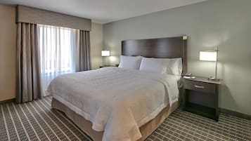Ein Hotelzimmer mit einem großen Bett, zwei Nachttischen, einer Lampe und einem Fenster mit Vorhängen.