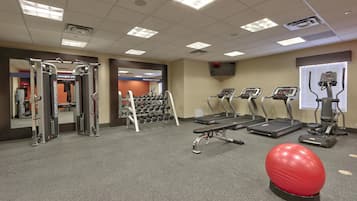 Une salle de sport équipée de matériel d’exercice, de tapis de course et d’un ballon rouge pour faire de l’exercice.