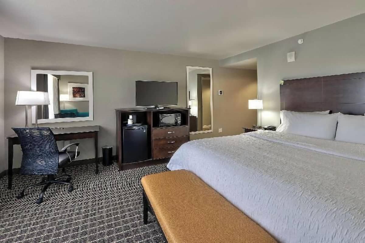 Una camera d'albergo con un letto, una scrivania con una sedia, una televisione e un comò.
