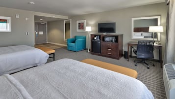 Habitación de hotel con dos camas, un escritorio con una silla, televisor, microondas y un espejo grande.