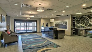 A hotel lobby with a reception desk, seating area, and a large window. - Hampton Inn & Suites Albuquerque Airport (Albuquerque)