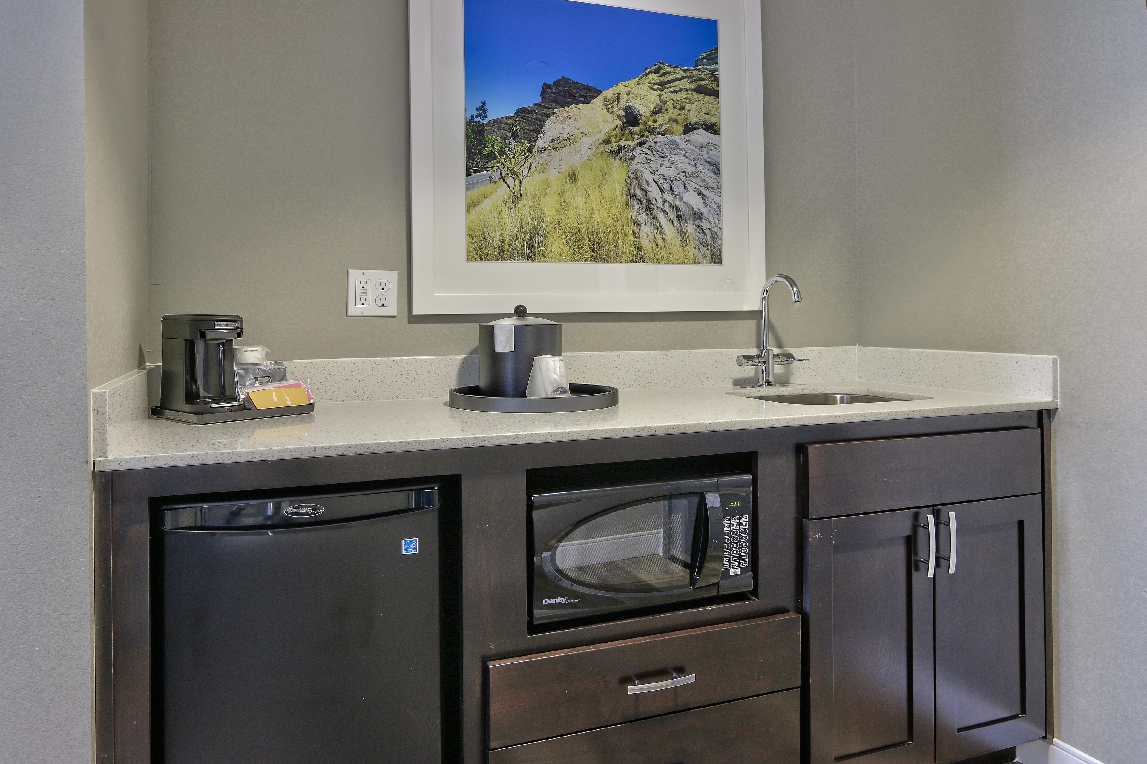A kitchenette with a coffee maker, microwave, and a sink.