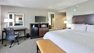 A hotel room with a bed, desk, chair, and a small table.