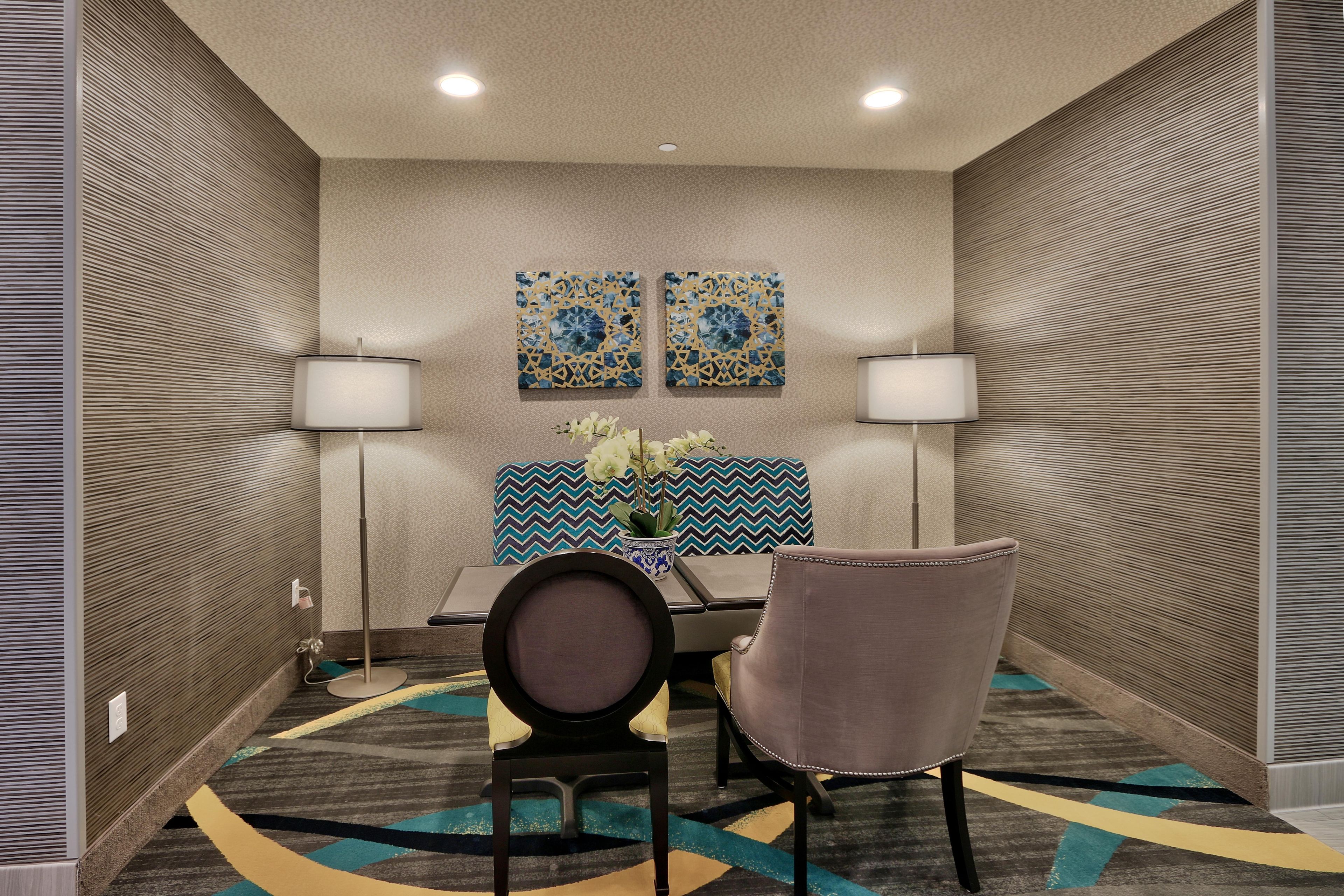 A conference room with two chairs, a table, and two wall-mounted lamps.