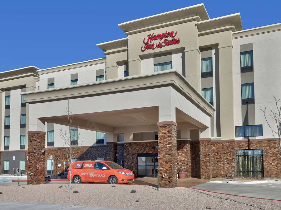 A Hampton Inn & Suites building with a modern design, featuring a covered entrance and a brick facade.
