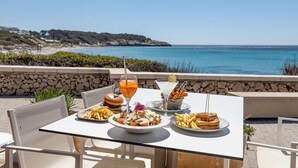 Una mesa con comida y bebidas, con vista a una playa y el océano.