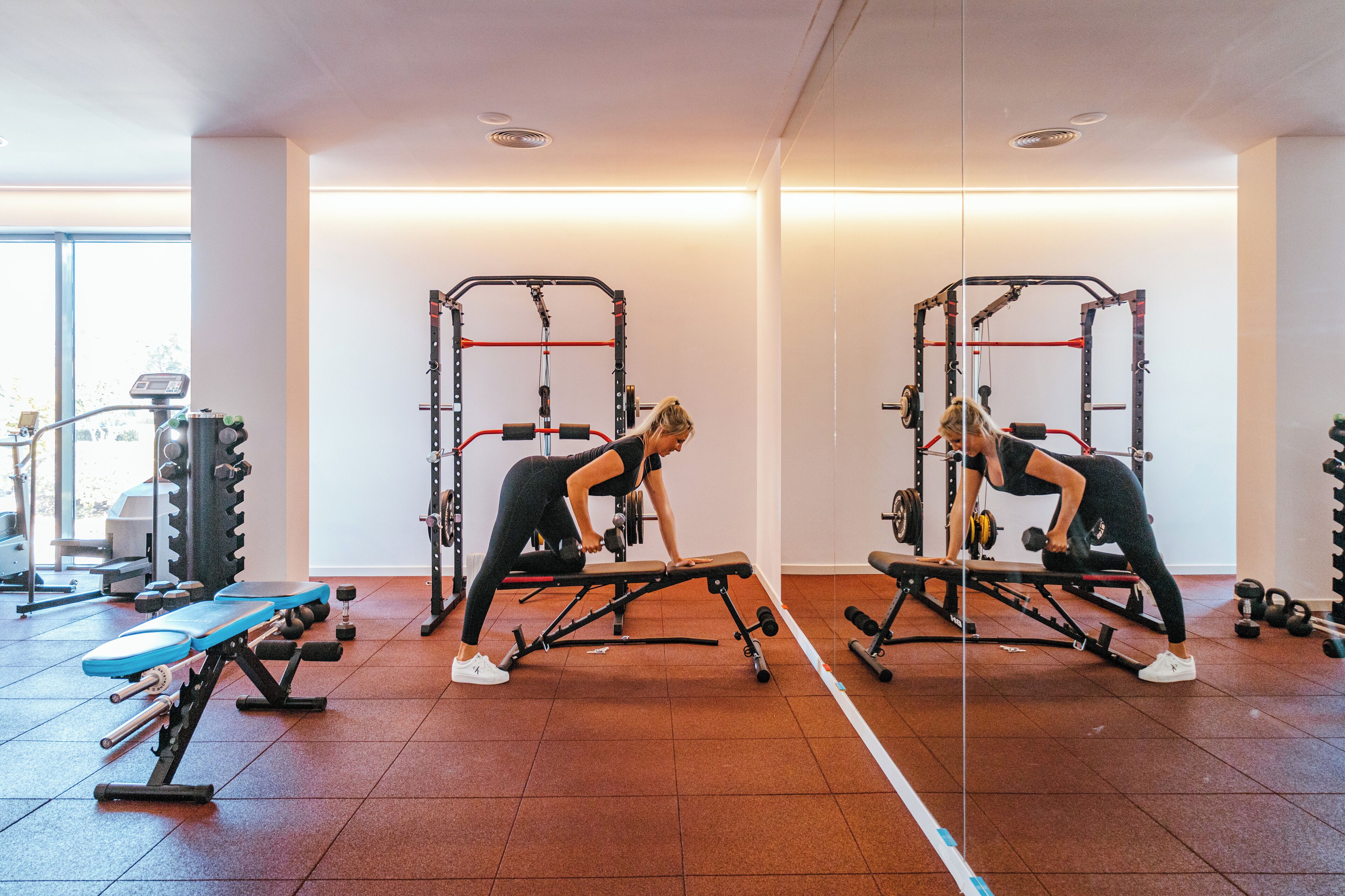 Un gimnasio con equipo de ejercicio, incluyendo bancos y máquinas de pesas.