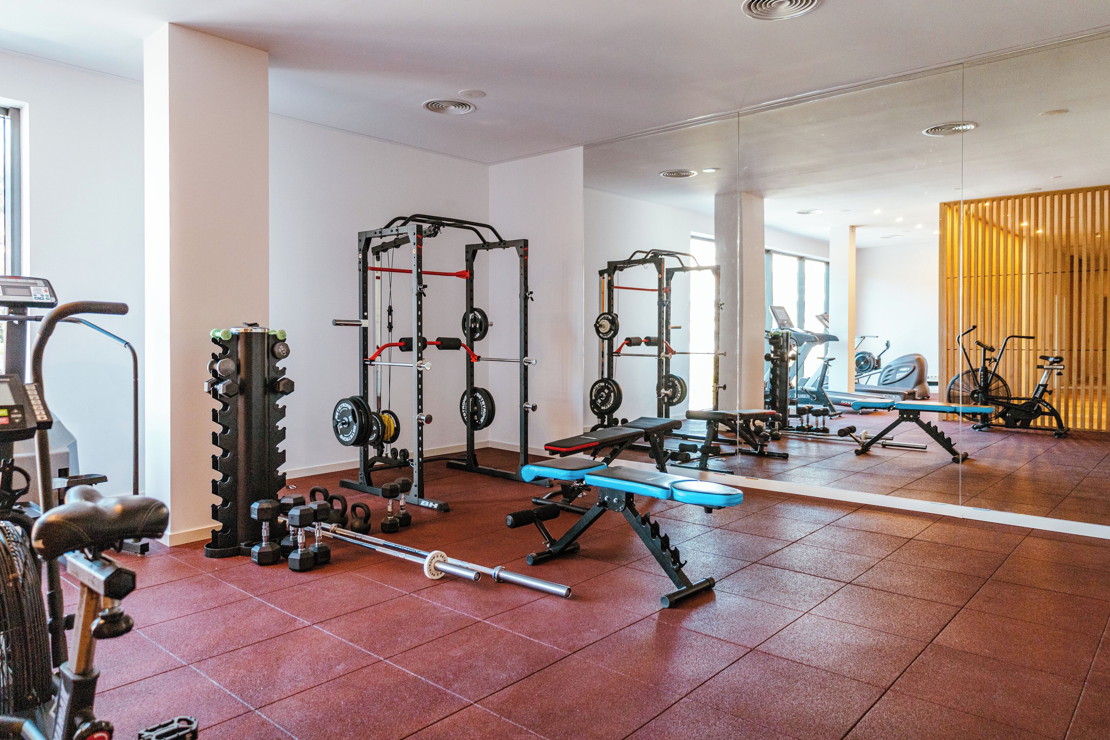 A gym with various exercise equipment, including weight machines, free weights, and cardio machines.