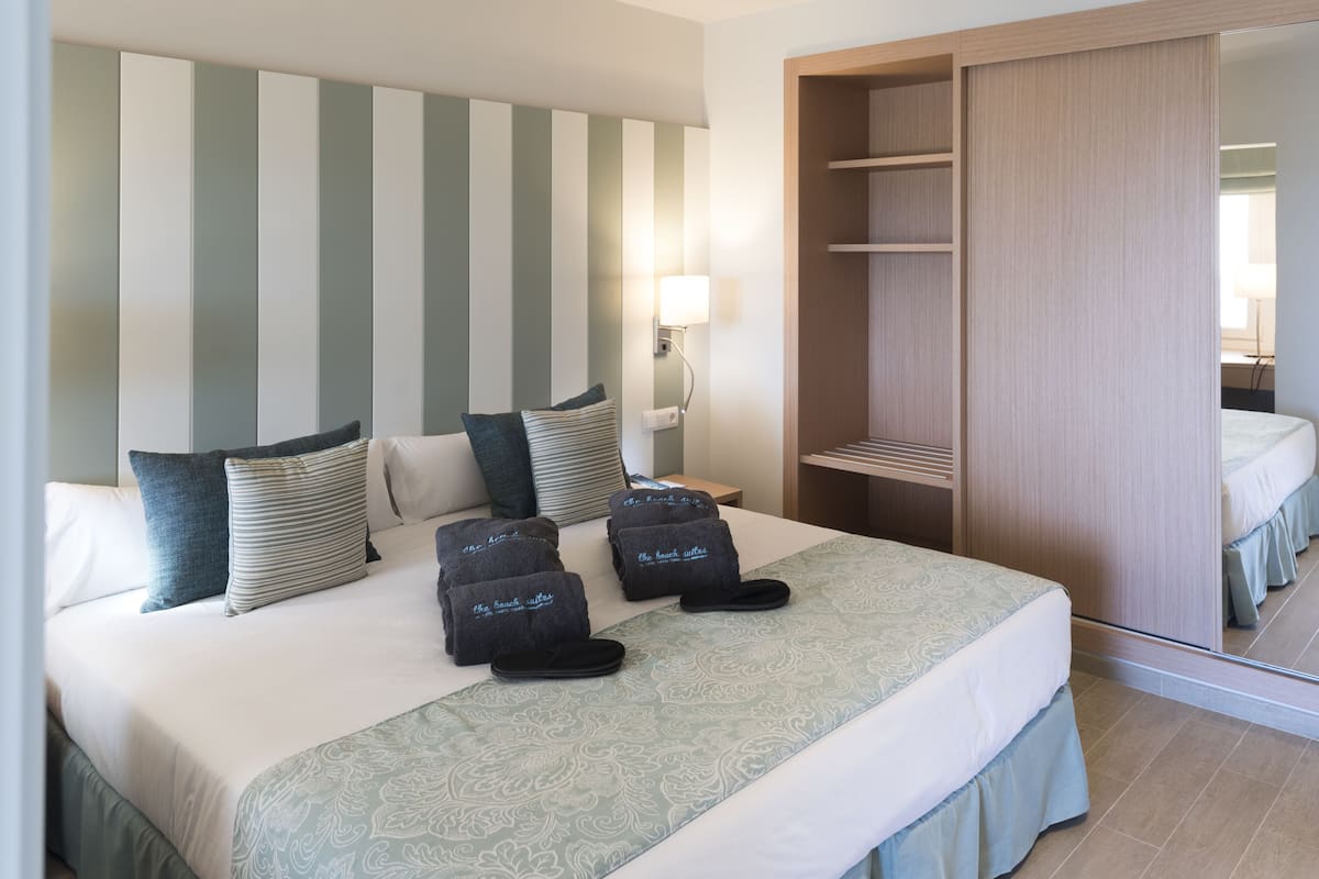 A hotel room with a large bed, striped headboard, and a wardrobe.