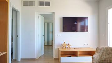 Una sala de estar moderna con un televisor de pantalla plana montado en la pared, un mueble de entretenimiento de madera y un sillón a cuadros.