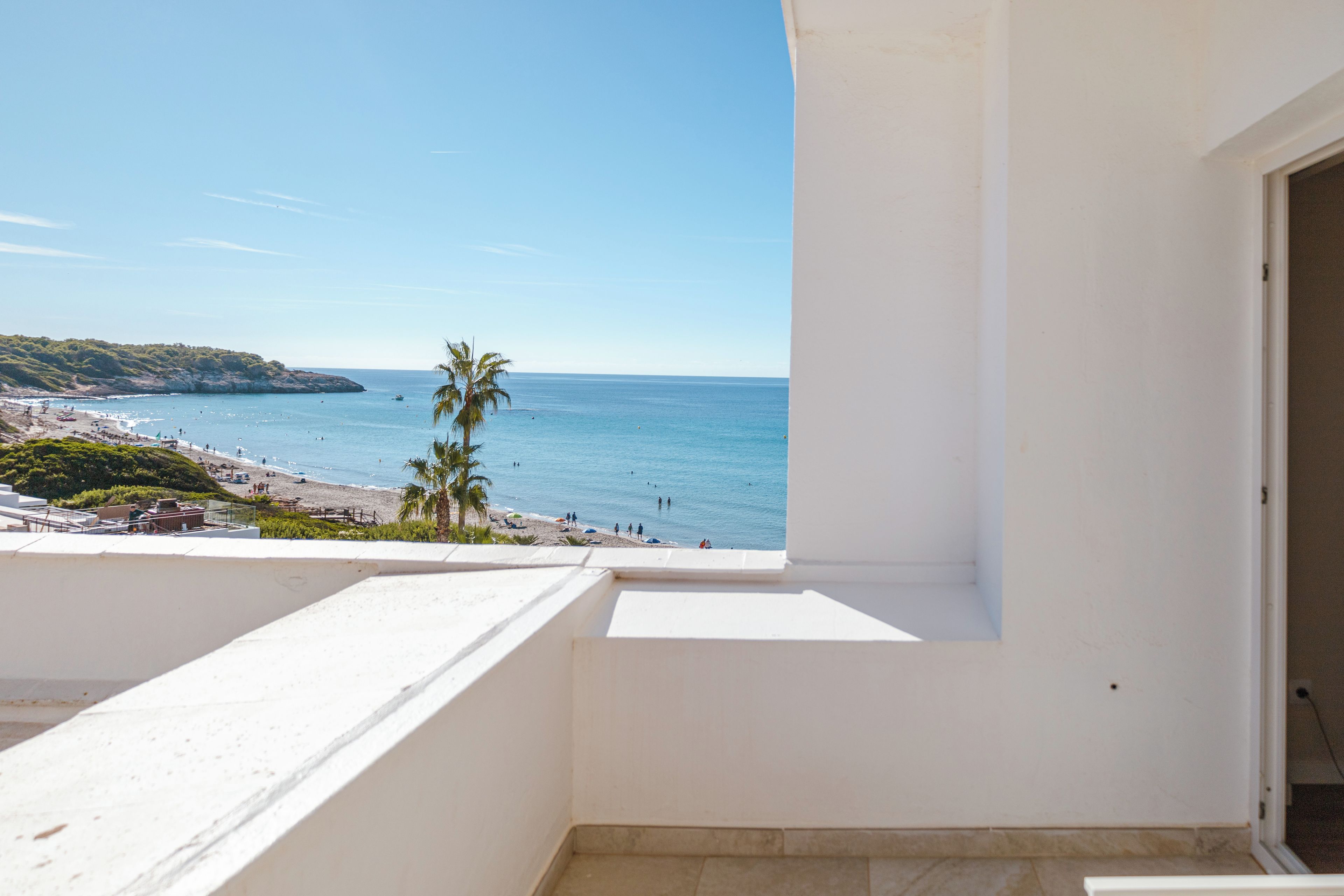 A balcony with a view of a beach and the sea.