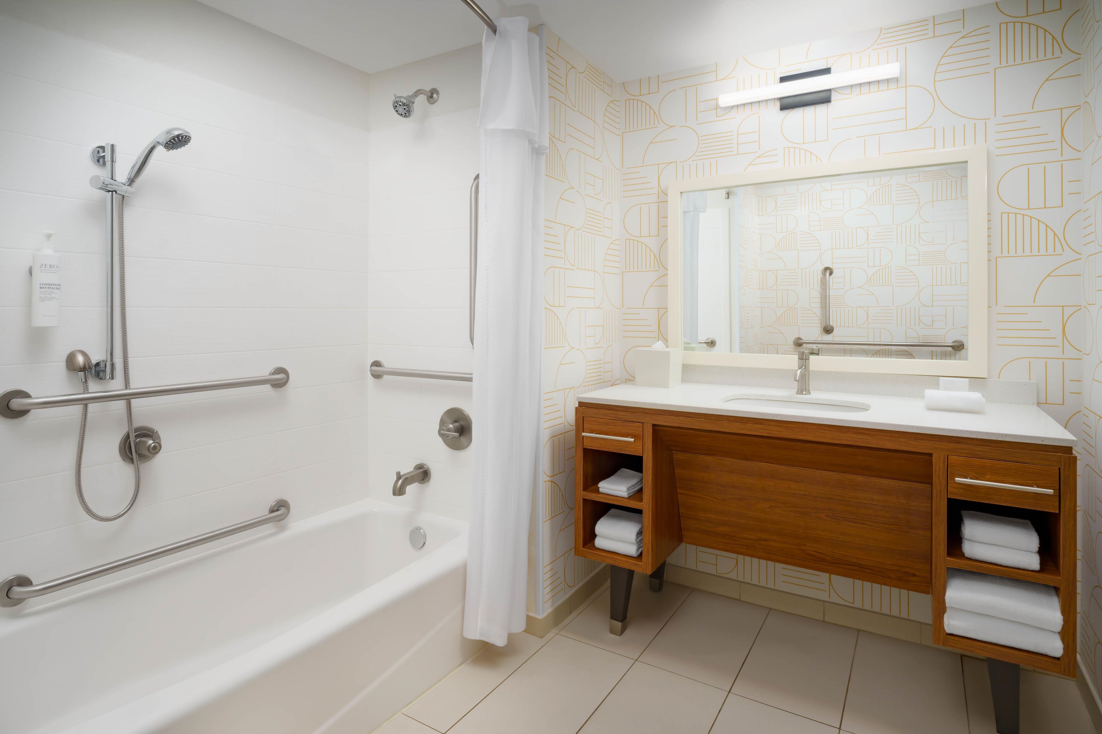 Ein Badezimmer mit einer Badewanne, einer Dusche und einem hölzernen Waschtisch mit Spiegel.