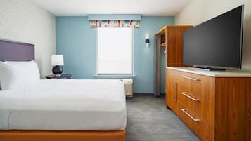 A hotel room with a bed, a television, a wardrobe, and a window with a curtain.