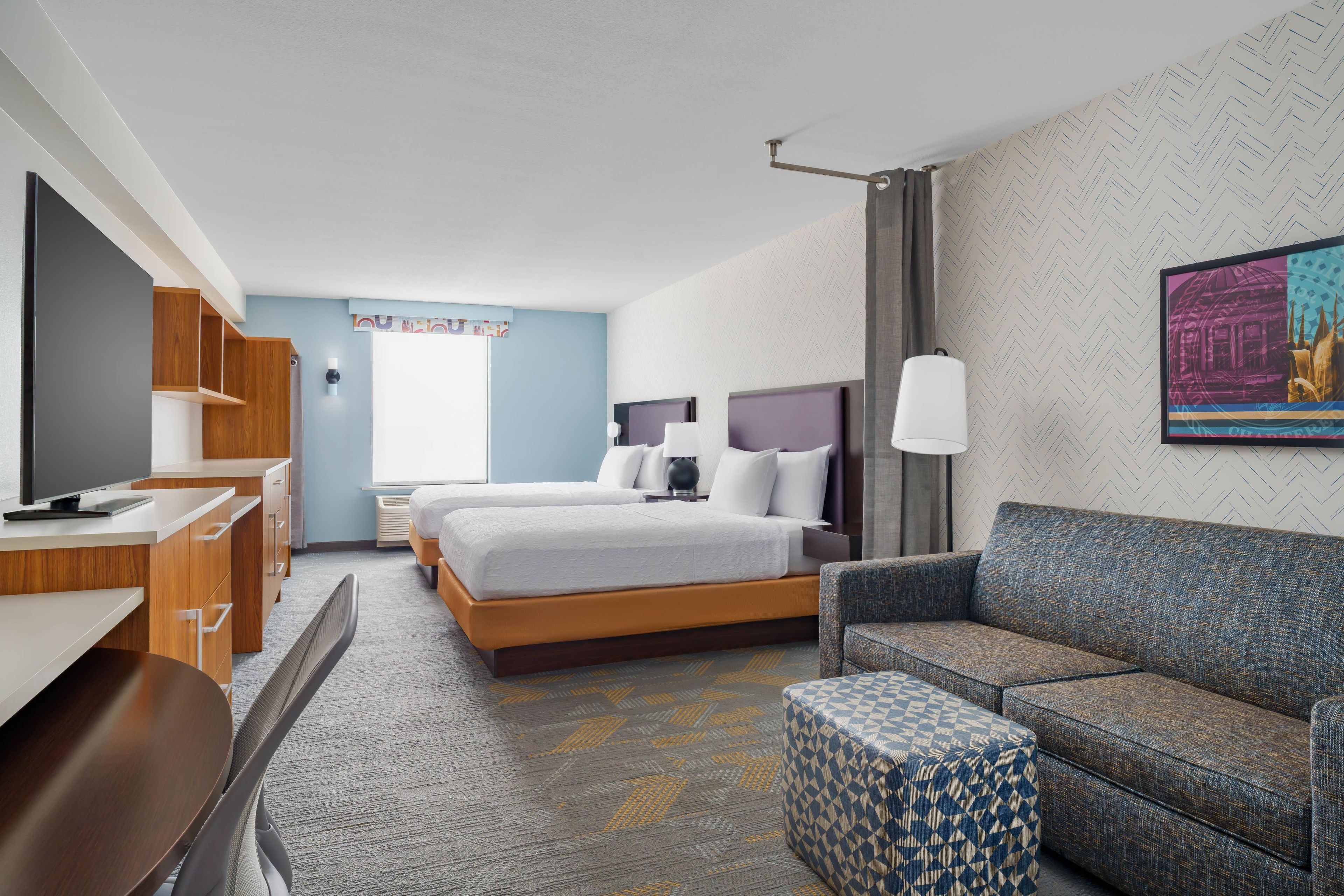 Ein Hotelzimmer mit einem Bett, einem Schreibtisch, einem Sessel, einer Couch und einer Wand mit Muster.