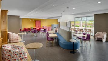 A modern dining area with multiple seating options including tables, chairs, and a sofa.