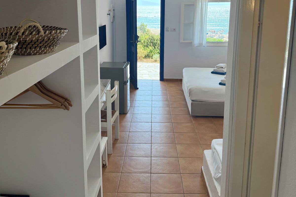 A hotel room with a bed, a desk, and a view of the sea.