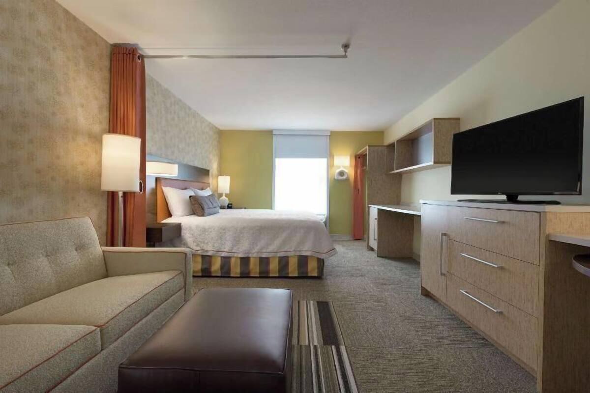 A hotel room with a bed, a sofa, a TV, and a desk.