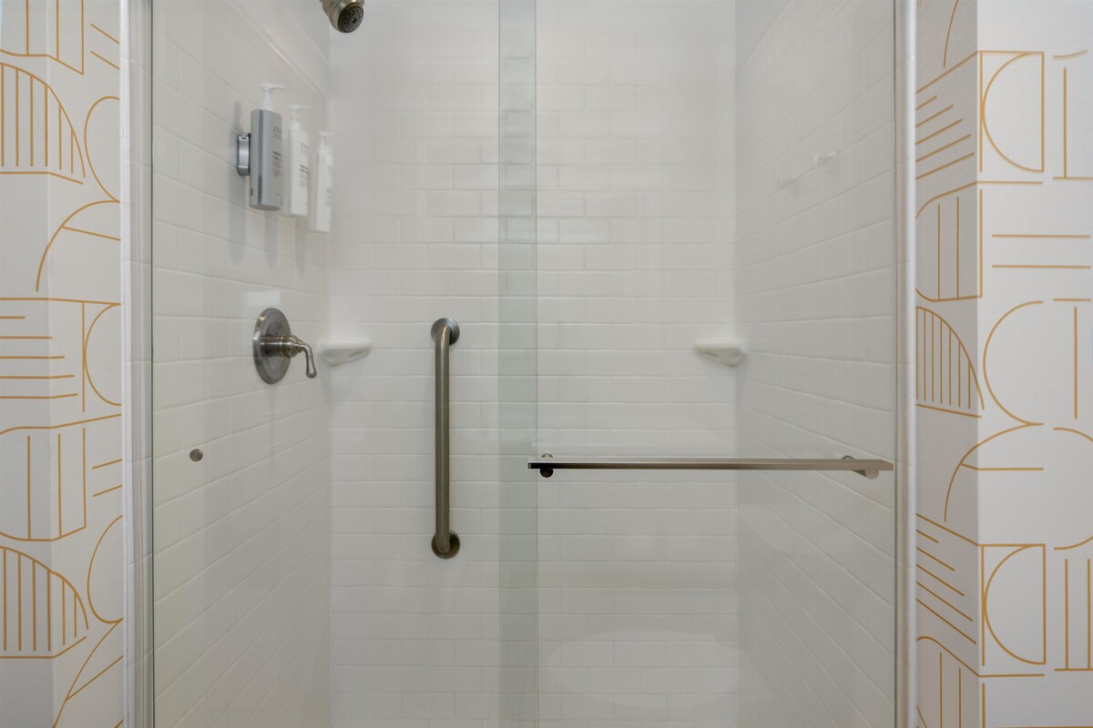 Une douche avec une porte en verre, un porte-serviettes et des articles de toilette fixés au mur.