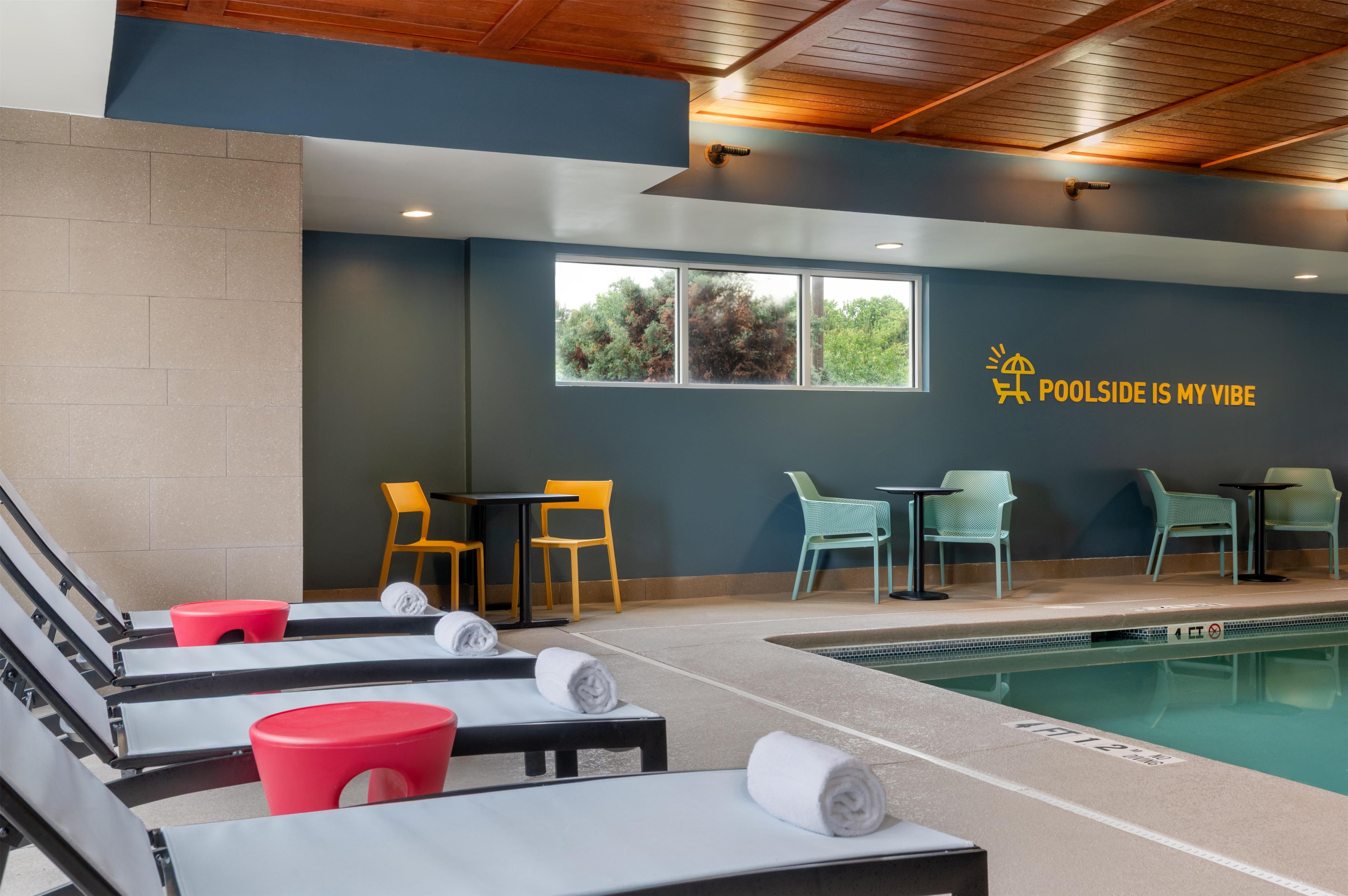 Zona junto a la piscina con sillones de descanso, una piscina y una pared con una ventana y un letrero.