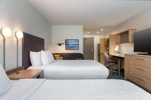 Ein Hotelzimmer mit zwei Betten, einem Schreibtisch, einem Fernseher und einem Bild an der Wand.