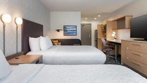 A hotel room with two beds, a desk, a television, and a painting on the wall.