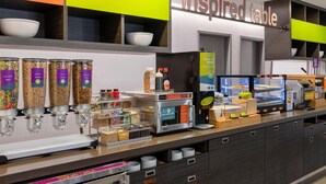 A breakfast bar with various food dispensers, a coffee machine, and a refrigerated display.