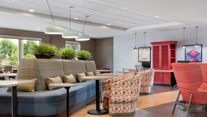 A modern lounge area with seating, tables, and potted plants.