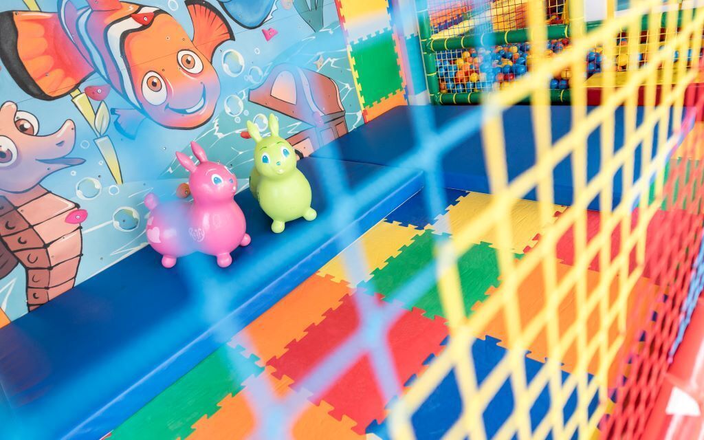 A colorful play area with a slide and foam mats.