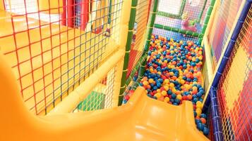 Zona de juegos con un tobogán amarillo y una piscina de pelotas llena de bolas multicolores.