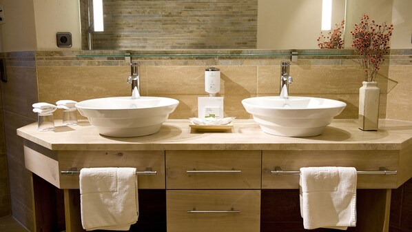 Une salle de bain avec deux lavabos, une étagère en verre et un miroir.