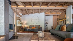 Een moderne woonkamer met een houten plafond, een bank, een salontafel en een open haard.