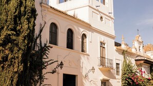 A white building with a bell tower, arched windows, and a door. - Hotel Cortijo el Esparragal (Gerena)