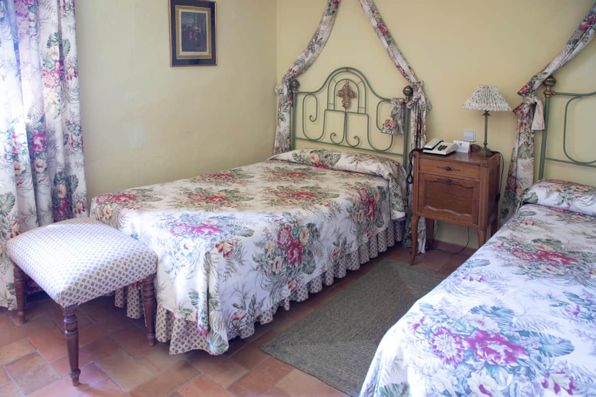 Une chambre à coucher avec un lit à baldaquin, une table de chevet, une chaise et une petite table.