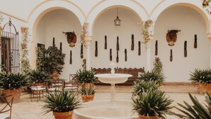 A courtyard with a central fountain, potted plants, and arches. - Hotel Cortijo el Esparragal (Gerena)