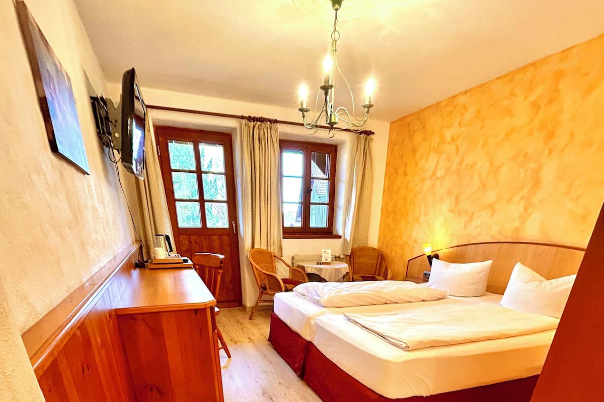 Een hotelkamer met een houten bureau, twee enkele bedden, een stoel en een tafeltje.