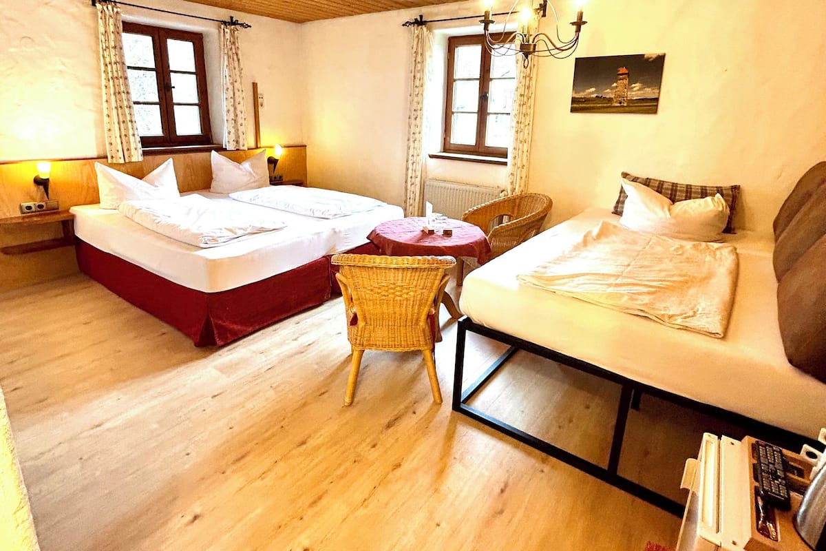 Een gezellige kamer met houten vloeren, een bed, een bank en een klein tafeltje.