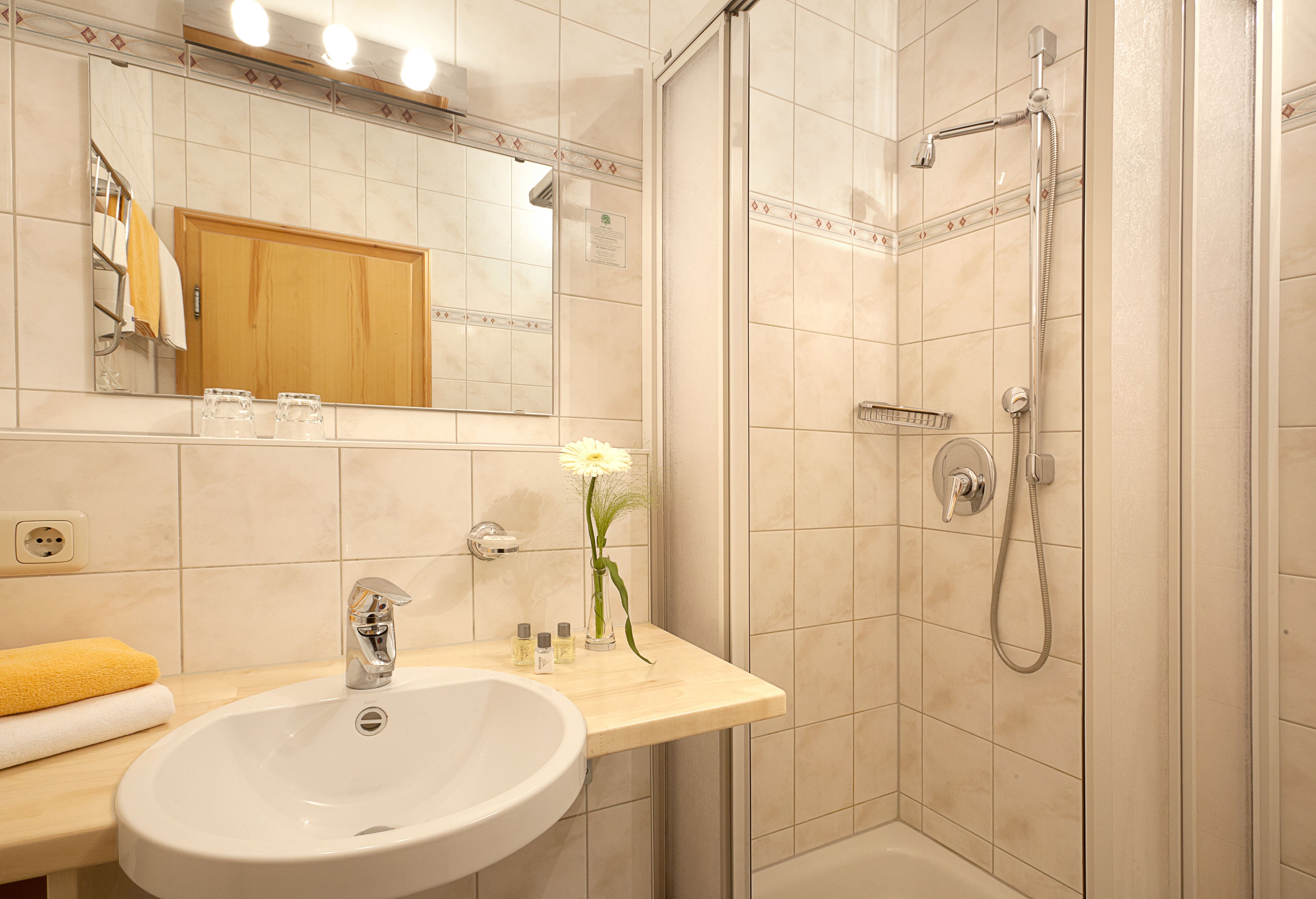 A bathroom with a sink, mirror, shower, and a towel rack.
