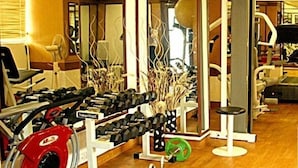 A gym with various exercise equipment including dumbbells, a Smith machine, and a bench.