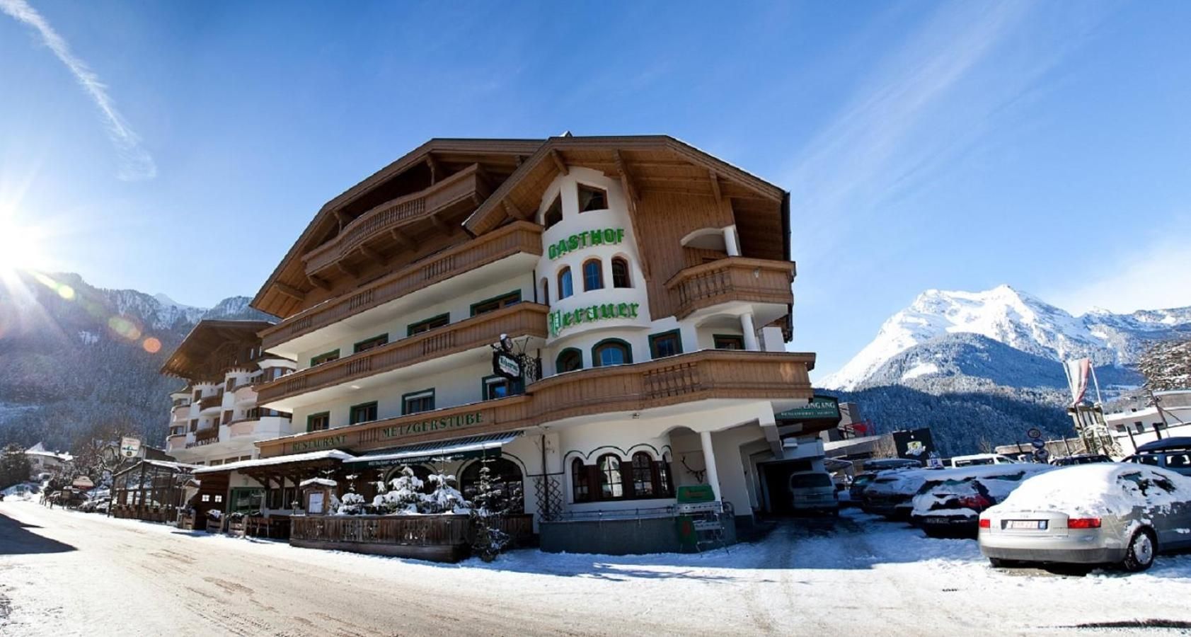 A multi-story hotel with a traditional Alpine architectural style, featuring balconies and a prominent sign.