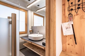 A modern bathroom with a round sink, a mirror, and a wooden vanity.